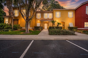 A yellow building with a red section, numbered 8405, and 8407, with a parking lot in front. - Charming 3-bedroom townhome in Kissimmee, perfect for family getaways! (Kissimmee)