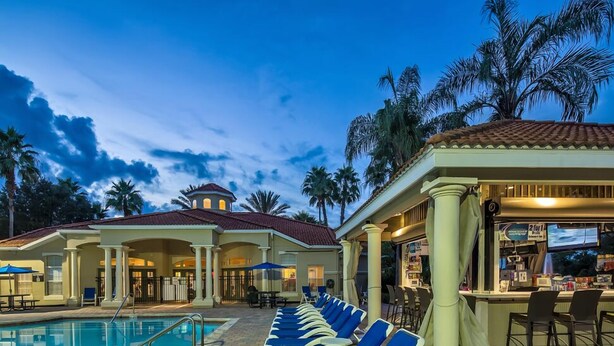 A pool area with lounge chairs and a bar. - Charming 3-bedroom townhome in Kissimmee, perfect for family getaways! (Kissimmee)