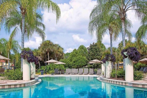 Relax by the serene pool surrounded by lush palm trees and tropical vegetation.