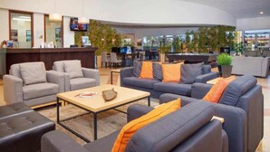 Een moderne lobby met banken, een receptiebalie en een zwembad.