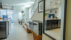 Una cocina moderna con armarios oscuros, un comedor con banco, y una escalera que lleva a un nivel superior.