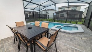 A covered patio area with a pool, a table, and chairs. - Spacious 5-bedroom home in Kissimmee, perfect for family getaways! (Kissimmee)