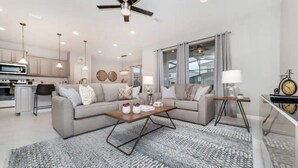 A modern living room with a sofa set, a coffee table, and a dining area with a lamp. - Spacious 5-bedroom home in Kissimmee, perfect for family getaways! (Kissimmee)