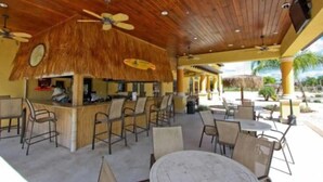 An outdoor bar area with wooden ceiling and ceiling fans, surrounded by outdoor seating with tables and chairs. - Spacious 4BR Kissimmee Townhome with Private Pool, sleeps 12 in Paradise Palms. (Kissimmee)