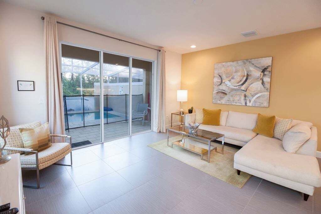 Un salon moderne avec un canapé, un fauteuil et une table basse. Une porte-fenêtre coulissante donne accès à un balcon.