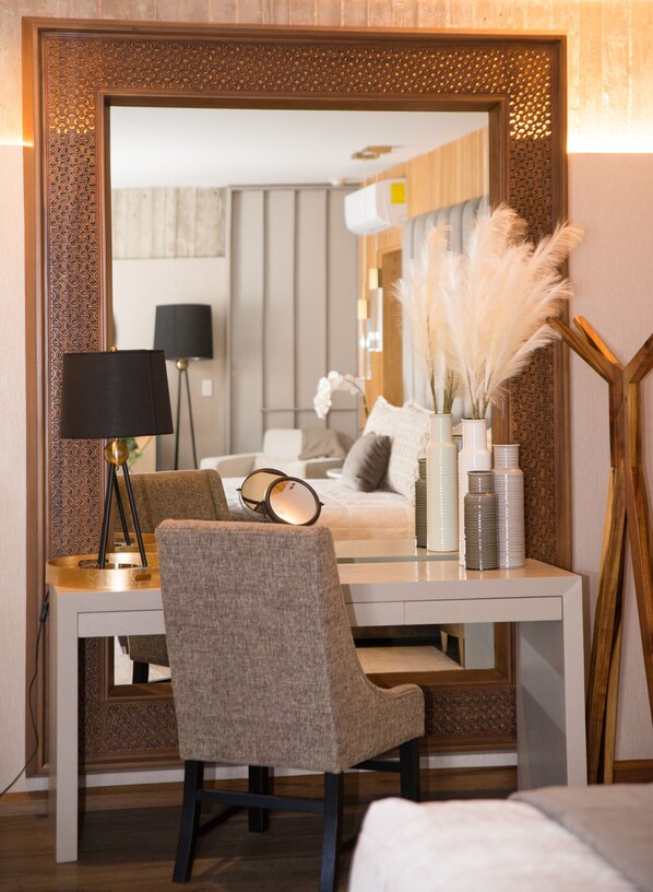 A hotel room with a large mirror, a desk with a lamp, a chair, and decorative items including pampas grass and vases. - Hotel Andana Resort (Valle de Guadalupe)