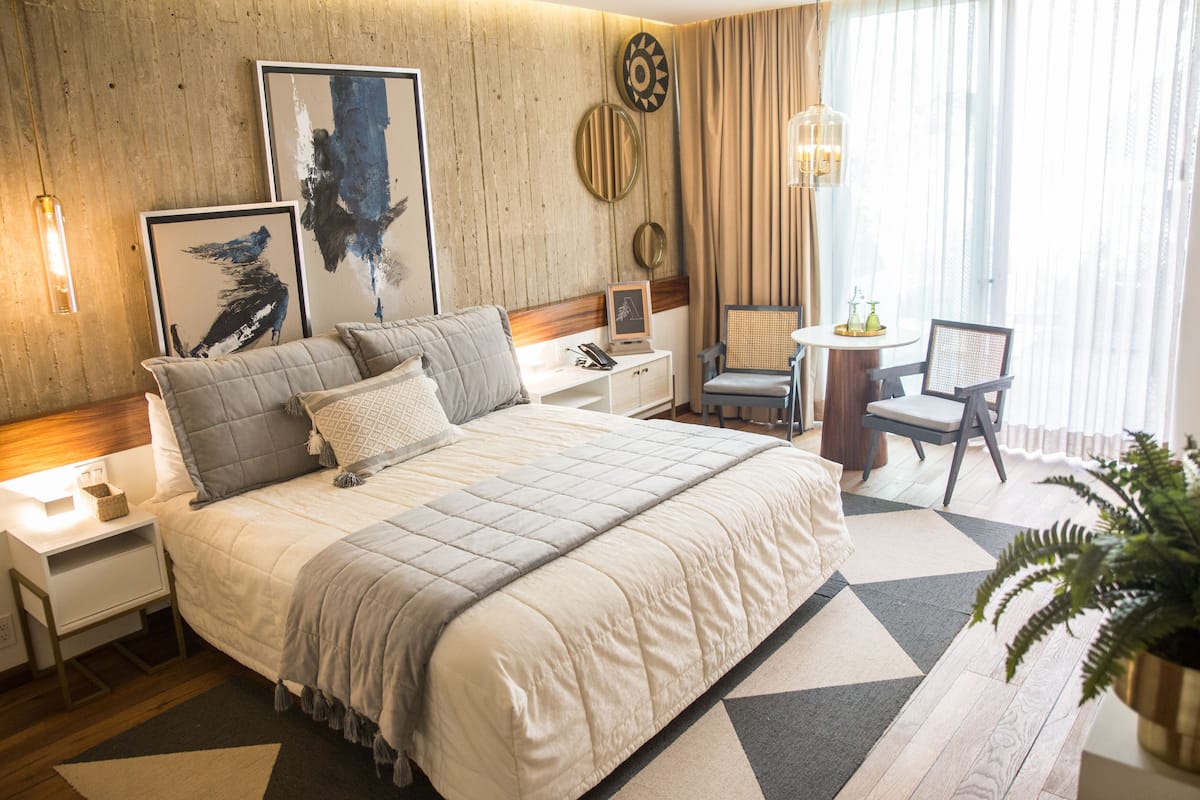Une chambre d’hôtel avec un grand lit, des tables de chevet, un bureau, une chaise et une plante en pot.