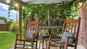 Two rocking chairs with patterned cushions, a small table, and a wooden bench with a hanging light fixture.
