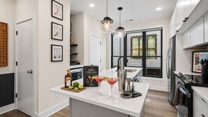 A modern kitchen with a central island, a bar area, and a large window providing natural light. - Rooftop • King Beds • Near Light Rail & LoSo (Charlotte)