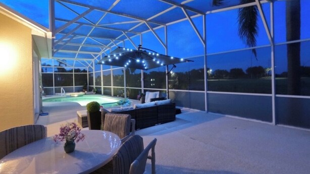 Un espacio al aire libre techado con un jacuzzi, asientos y una mesa con flores.