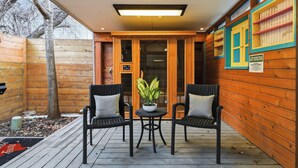 Une terrasse en bois avec deux fauteuils en osier et une petite table sur laquelle est posée une plante.