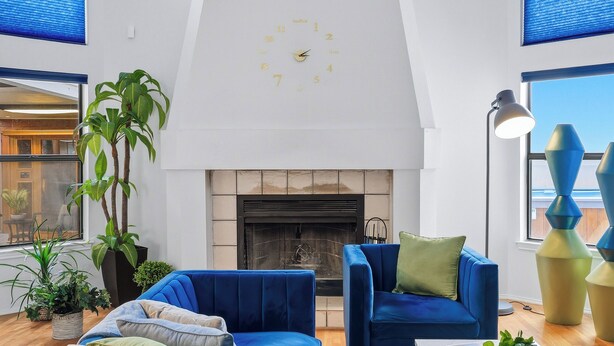 Un salon moderne avec une cheminée, des canapés bleus et de grandes fenêtres.