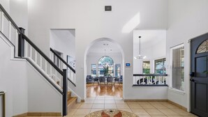 Un hall d’entrée spacieux, doté d’un sol carrelé, d’une arche centrale et d’un escalier situé sur le côté gauche.