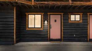 A log cabin with three doors, each with a window. - Standard Room w/ King Bed, Balcony, Fireplace, Mountain Views Room #13 (Lake Placid)