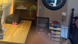 Une pièce avec un bureau en bois, une lampe, un miroir et un lit.