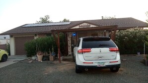 Un VUS blanc est garé devant une maison dotée d’un garage, de panneaux solaires sur le toit et d’un porche abrité.