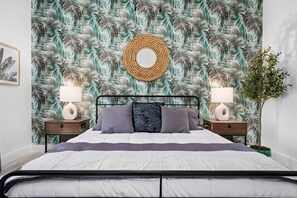 Cozy retreat with a central bed, bedside tables, and a tropical leaf pattern on the walls.