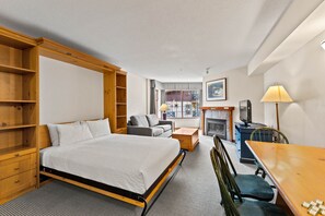 Une chambre d’hôtel comprenant un lit, un bureau, une chaise, un canapé, une télévision, une lampe et une cheminée.