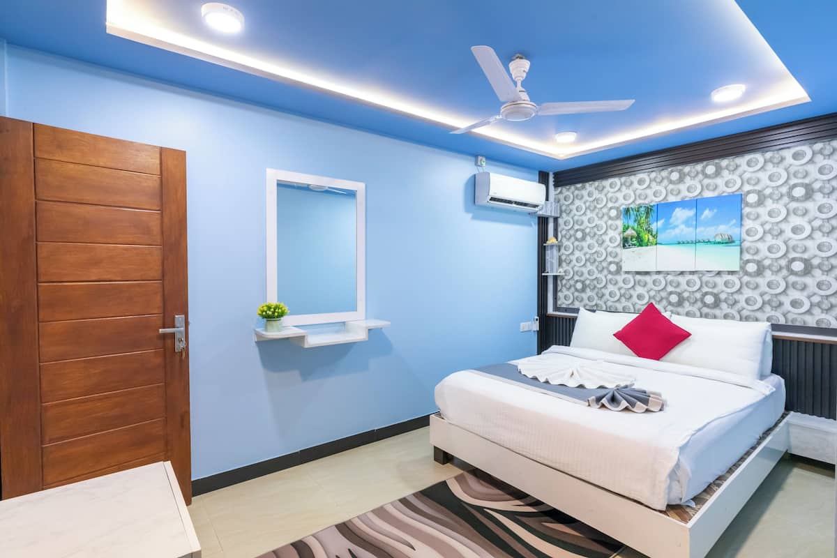 A bedroom with a bed, a ceiling fan, an air conditioning unit, a wall-mounted shelf, and a patterned wall.