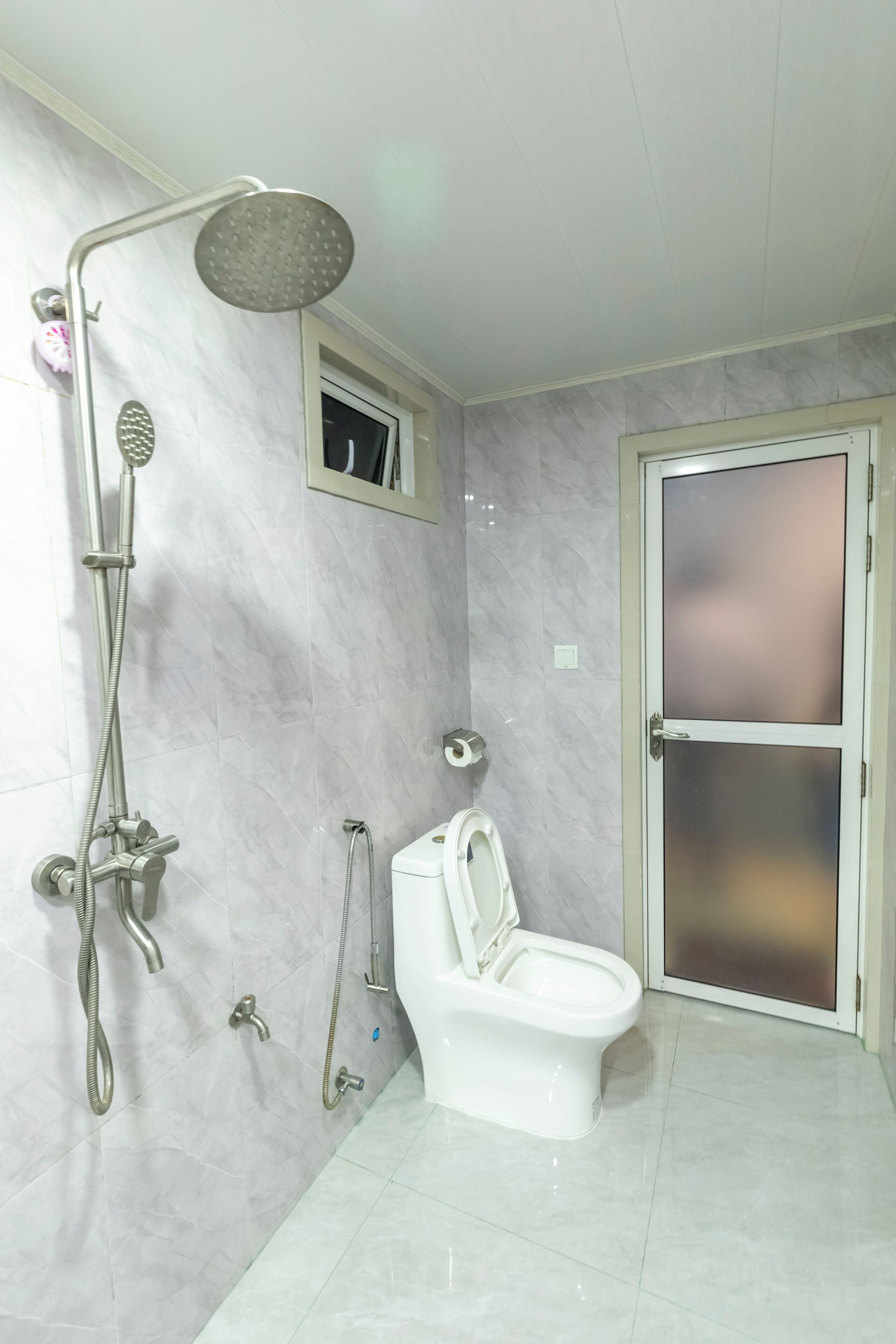 Un baño con ducha, inodoro y puerta.