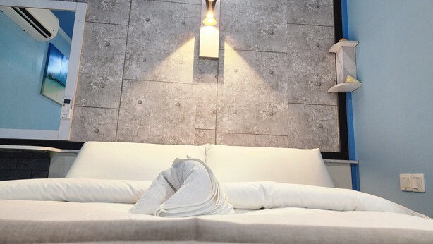 Une chambre d’hôtel avec un lit, une lampe fixée au mur et un appareil de climatisation visible.