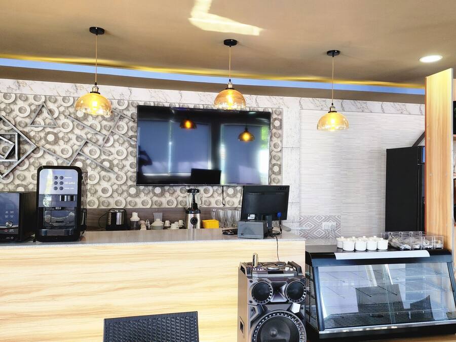 L’intérieur d’un café moderne, avec un comptoir en bois, une machine à expresso et un grand téléviseur à écran plat.