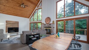 A spacious living room with a large wooden dining table, a fireplace, and a television.