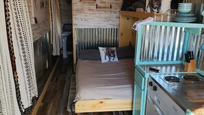 A compact, rustic room with a bed, kitchenette, and wooden ceiling. - Teeny Home in the Black Hills! (Custer)