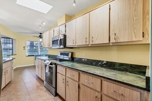 Kitchen features stainless steel appliances, a window with outdoor views, and a skylight.