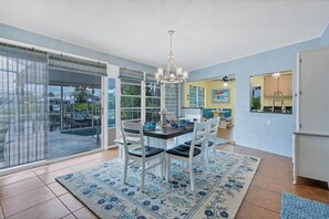 Enjoy meals in this spacious dining area with a large table for four, surrounded by comfortable chairs and a stunning chandelier.
