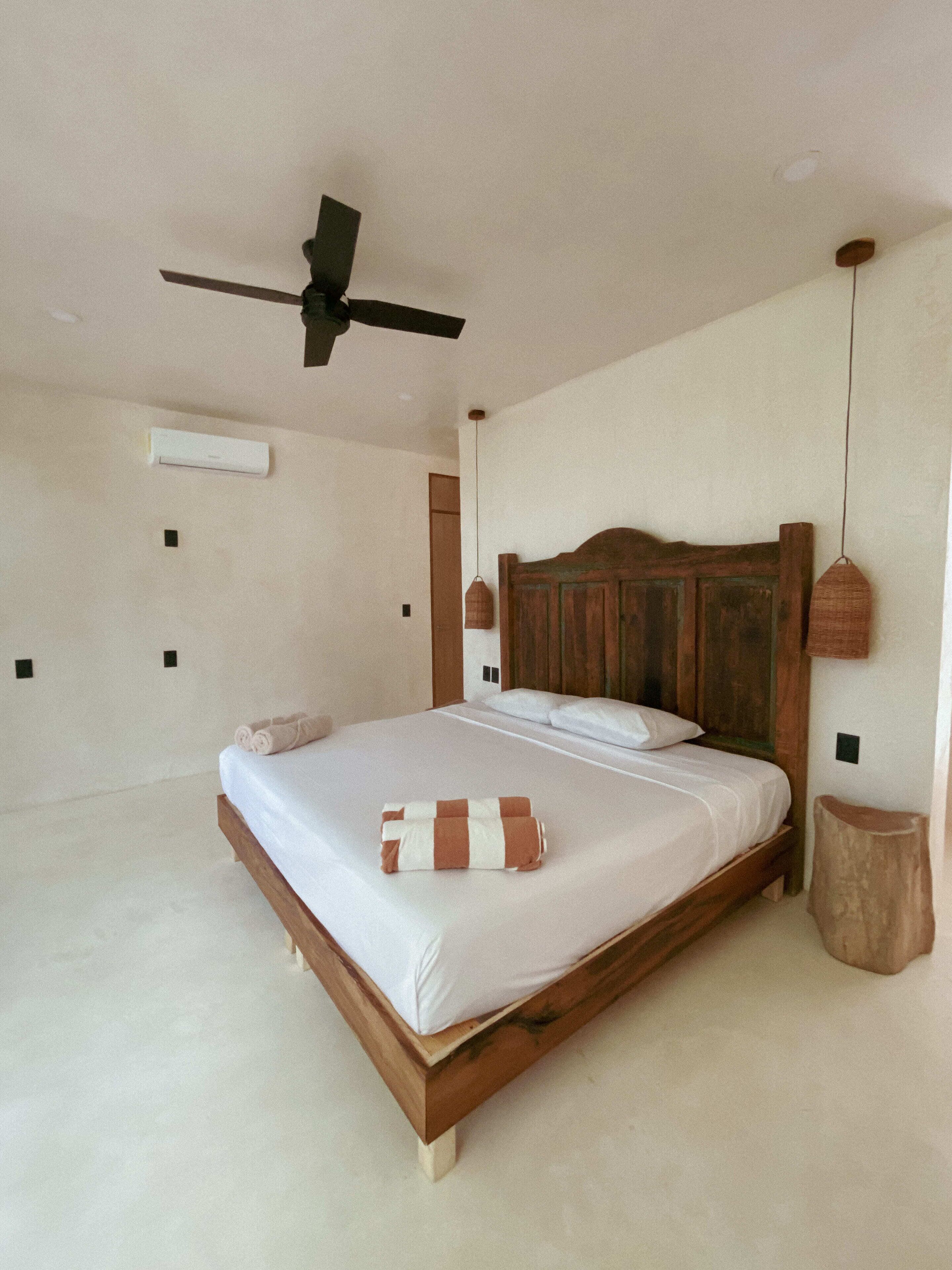 Ein Schlafzimmer mit einem hölzernen Bett, einem Deckenventilator und einem Nachttisch.