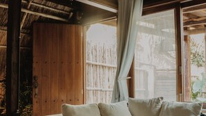 A wooden room with a built-in sofa, a window with curtains, and a thatched roof. - BoaBoa Bacalar (Bacalar)