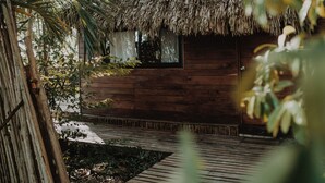 A thatched-roof hut with a wooden exterior, surrounded by lush greenery and a wooden deck. - BoaBoa Bacalar (Bacalar)