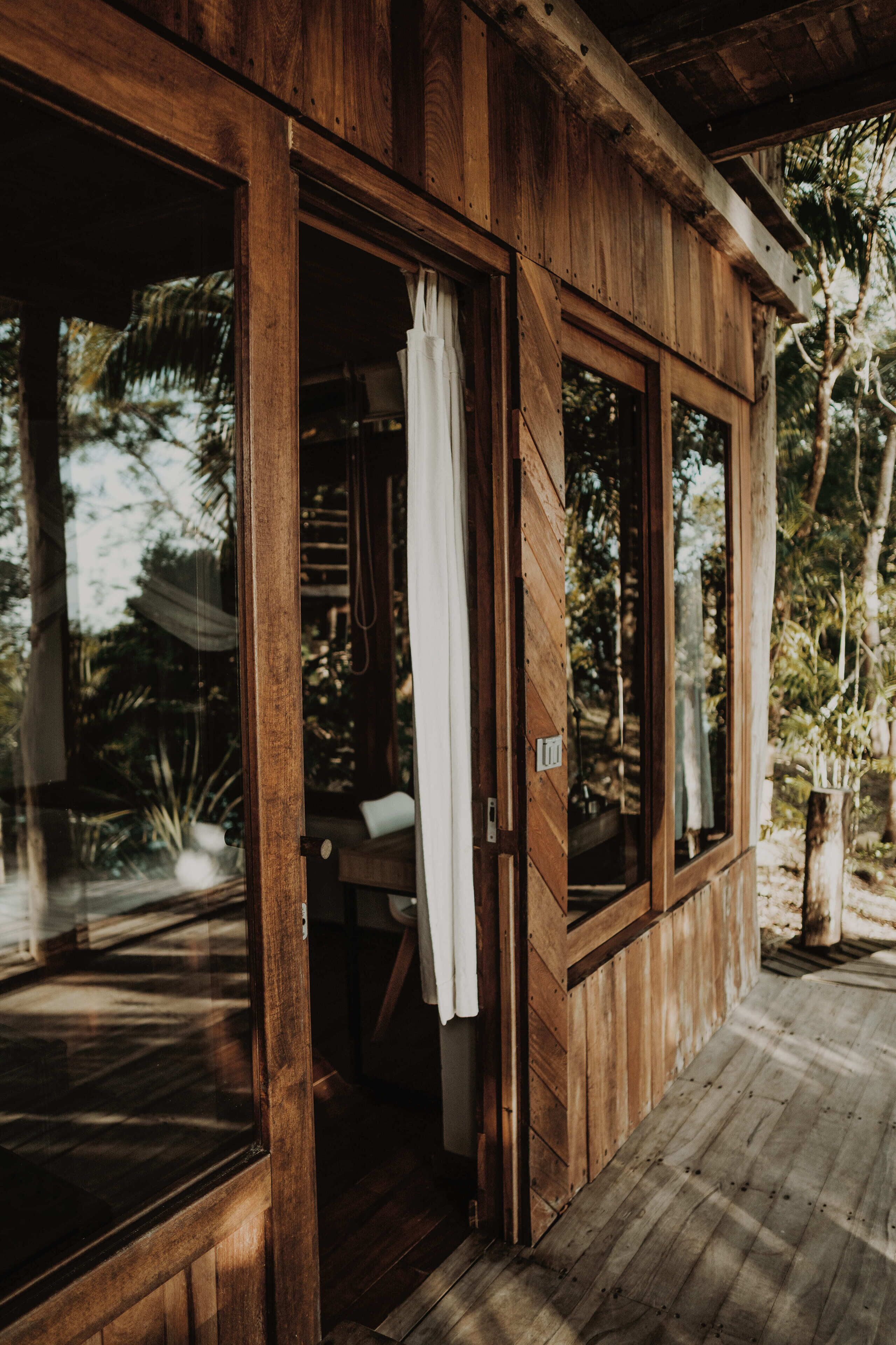 Une cabane en bois dotée de grandes fenêtres et d’une terrasse en bois.