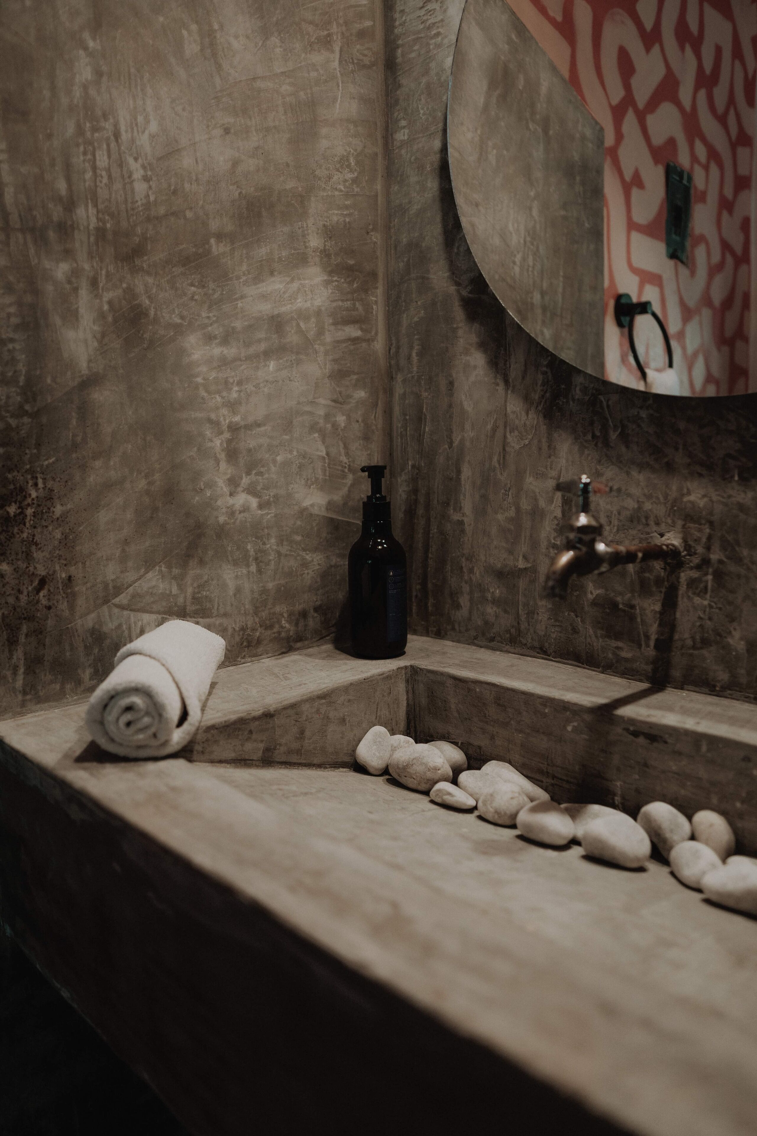 Un baño con un lavabo de piedra, una toalla y un dispensador de jabón.