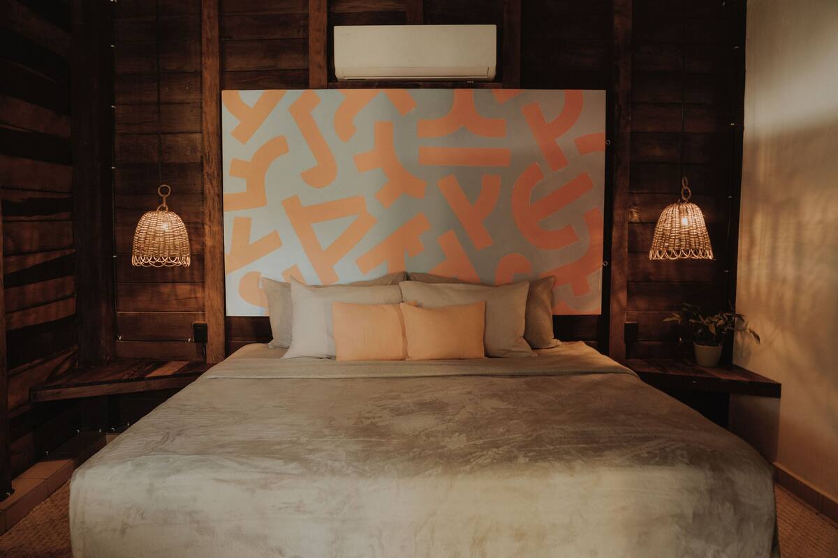 Un dormitorio con una cama grande, paredes de madera y dos lámparas fijadas a la pared.