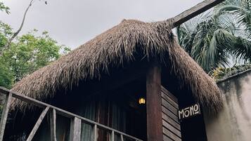 A wooden structure with a thatched roof, a sign reading 'MONO', and a staircase leading up to it.