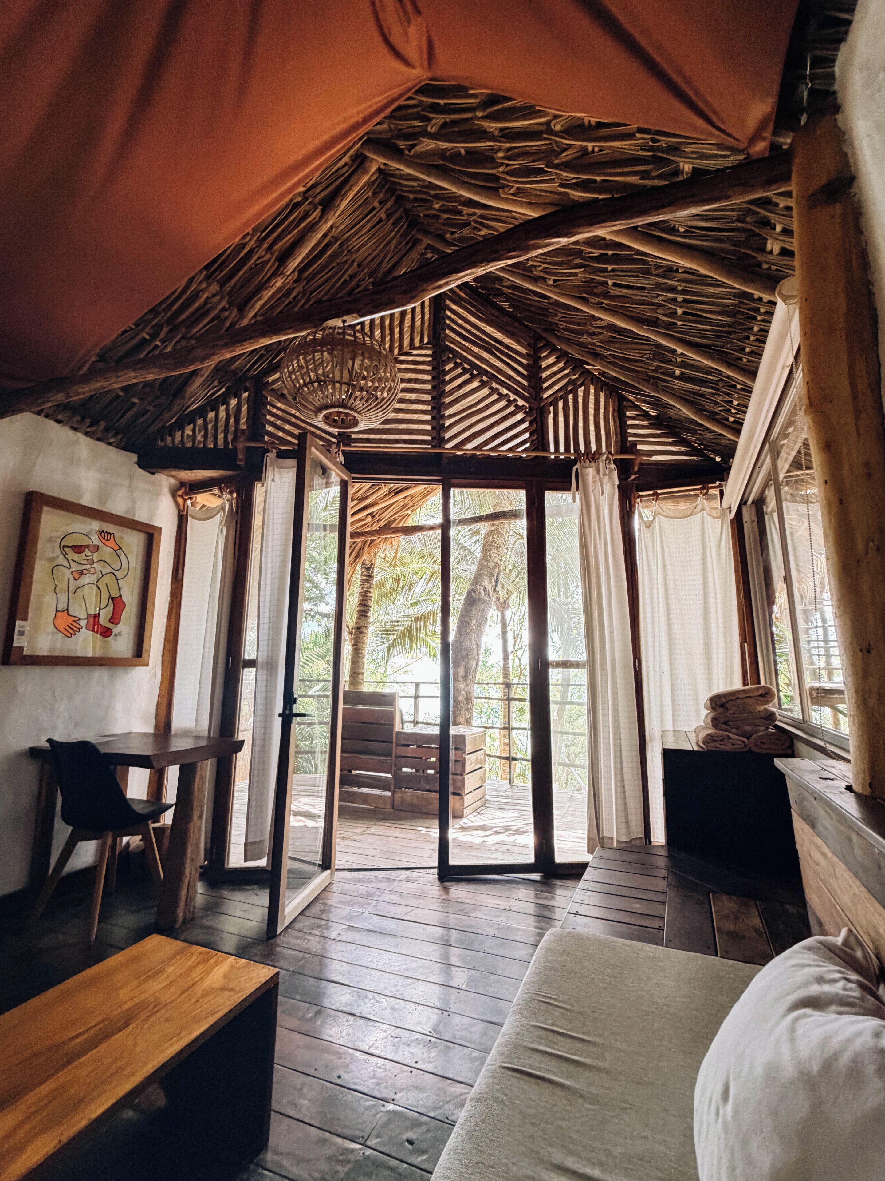 A room with a wooden ceiling, a sofa, a table, and a bench.