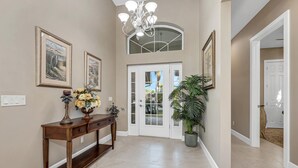 A hallway with a wooden console table, a potted plant, and framed artwork on the walls. - Dockside Shore- Waterfront Home in Bayshore Arts District of Naples (Naples)