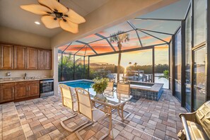 A spacious patio with a glass enclosure, a pool, and a dining area with outdoor furniture.