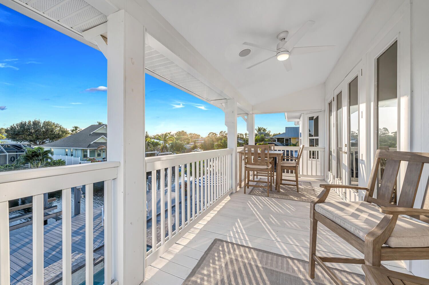 A covered porch with a table and chairs, a ceiling fan, and a view of the neighborhood.