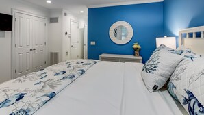 A bedroom with a bed, a nightstand, a mirror, and a ceiling fan.