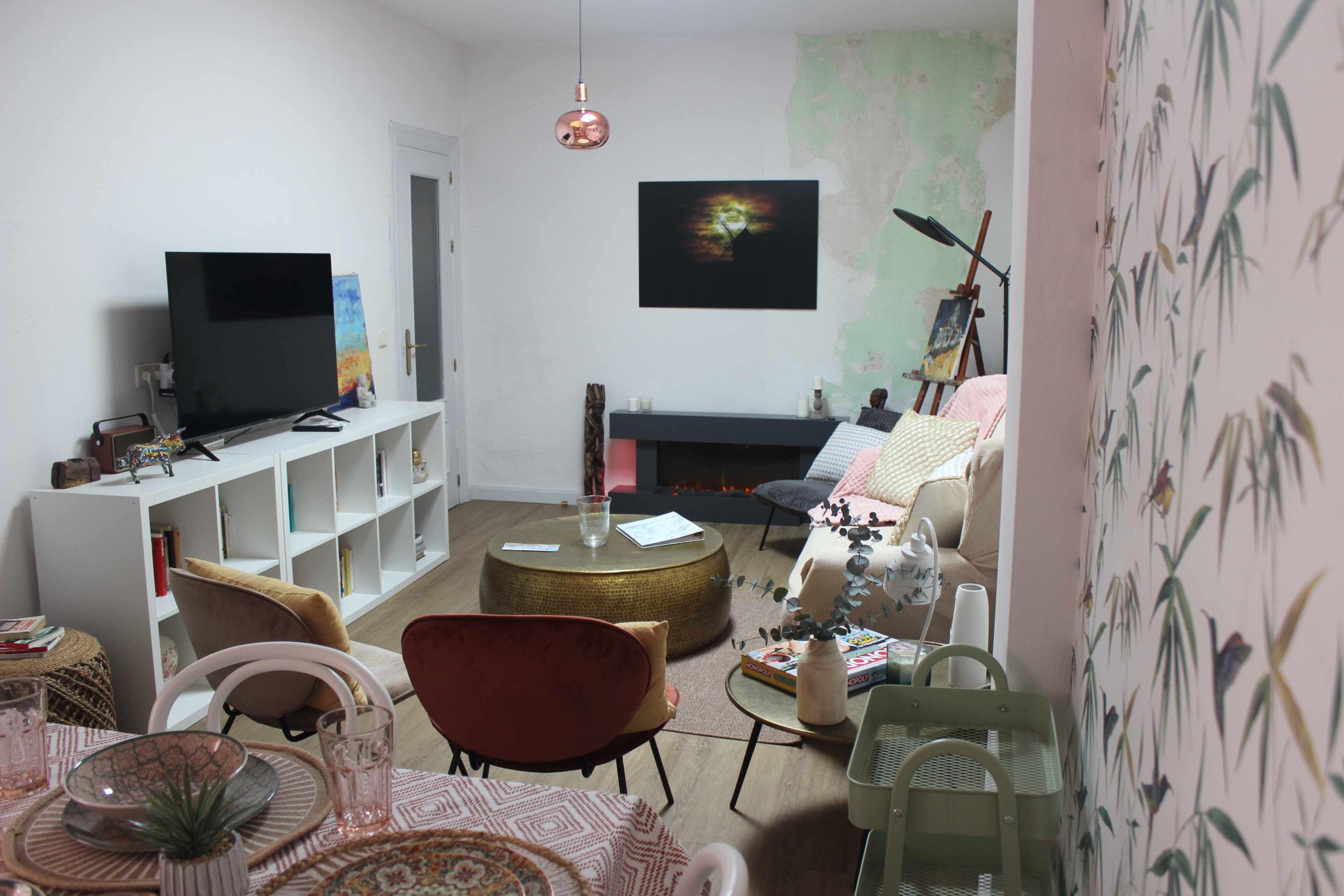 Ein Wohnzimmer mit Fernseher, Sofa, Couchtisch und Bücherregal.