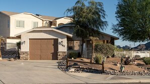 A single-story house with a garage, a small front yard with rocks and a cactus, and a mountain in the background. - La Shoshone Casita Rio (Lake Havasu City)