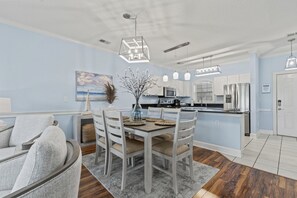 A modern kitchen with white cabinets, a dining table with chairs, and pendant lighting.
