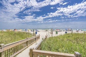 A wooden boardwalk leading to a beach with umbrellas and beach chairs. - Beach & golf! Perfect location for all activities (Myrtle Beach)