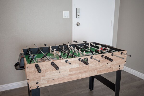A wooden foosball table with black and white players, set against a plain wall with a door in the background. - Spacious Luxury Retreat - Close to the Strip (Las Vegas)