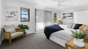 A modern bedroom with a bed, a chair, a desk, and a large window. - Central Tropical Oasis with Pool - Pet Friendly (Noosaville)