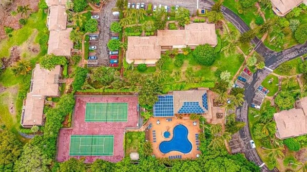 An aerial view of a resort with multiple buildings, a swimming pool, tennis courts, and solar panels. - Molokai condo Pool/Spa, 2 bedrooms/2 bathrooms. Walking distance to the beach. (Maunaloa)