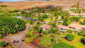 An aerial view of a resort with multiple bungalow-style buildings, surrounded by lush greenery and palm trees. - Molokai condo Pool/Spa, 2 bedrooms/2 bathrooms. Walking distance to the beach.  (Maunaloa)
